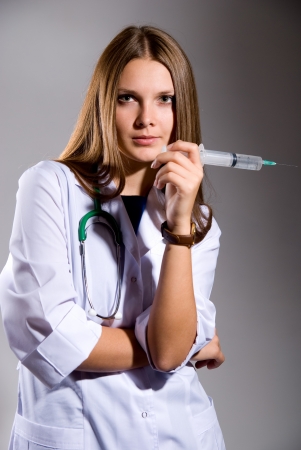 Female doctor with big syringe on grey backgroundの写真素材