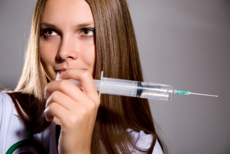 Woman doctor with big syringe on grey backgroundの写真素材