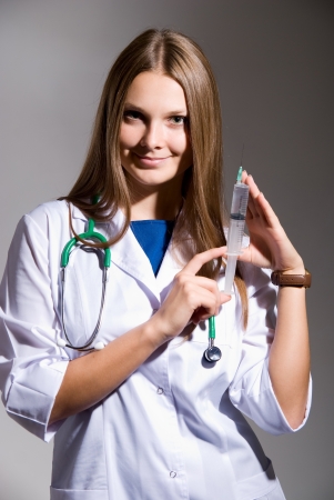 Doctor holding a syringe in his hand.on grey backgroundの写真素材