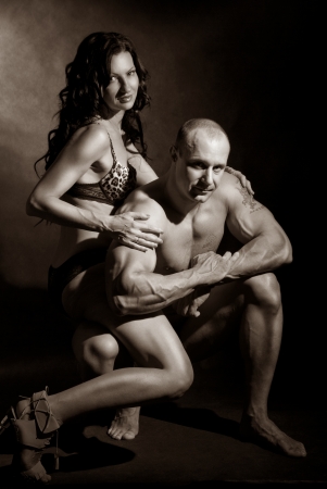 Muscular man and a woman posing in studio on dark background toningの写真素材