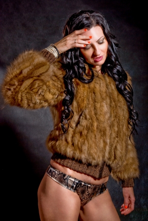 Beautiful sexy woman in fur coat on blackの写真素材