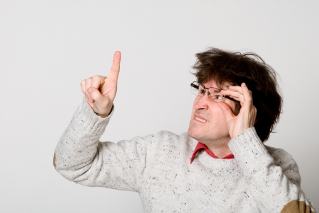 Man with glasses and with disheveled hair pointing at something interesting over light backgroundの写真素材