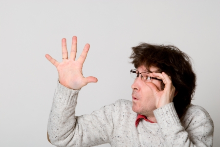 Man with disheveled hair pointing  hand at something interesting over light backgroundの写真素材