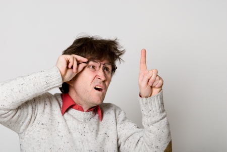 Man with glasses and with disheveled hair pointing at something interesting over light backgroundの写真素材