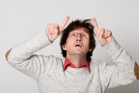 Man with disheveled hair pointing two fingers at something interesting over light backgroundの写真素材