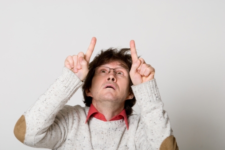 Man with disheveled hair pointing two fingers at something interesting over light backgroundの写真素材