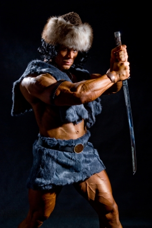 Male warrior with a sword in the form of a barbarian on a black backgroundの写真素材