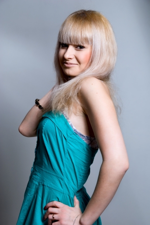 Portrait of a beautiful blonde in a blue dress on a gray backgroundの写真素材