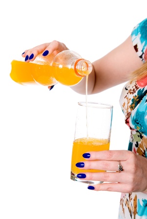 Woman pouring orange juice from a bottle into a glass. part of body. on backgroundの写真素材