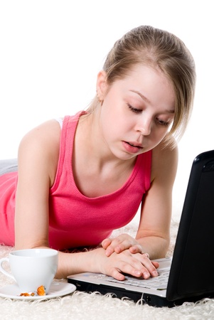Cheerful girl lying on the floor and working on a laptop.の写真素材