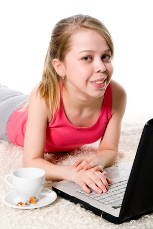 Cheerful girl lying on the floor in front of her laptop.の写真素材