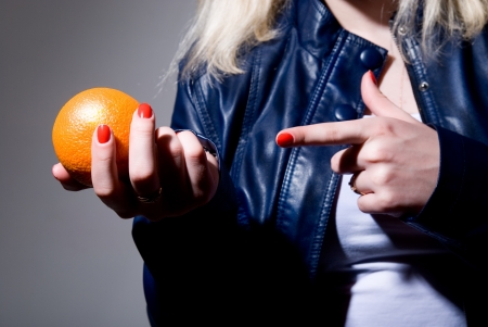 Close-up of a finger pointing to an orange. part of bodyの写真素材