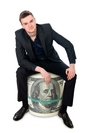 The young successful businessman sitting on a roll of money. Isolated on white backgroundの写真素材