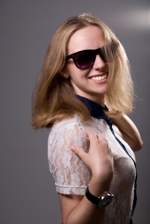 portrait of a cheerful happy girl in sunglasses on a gray backgroundの写真素材