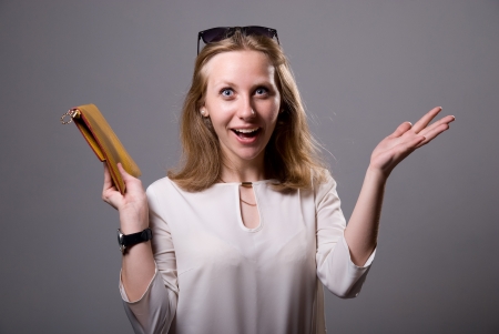 Portrait of a surprised girl in sunglasses holding a clutch. On a gray backgroundの写真素材