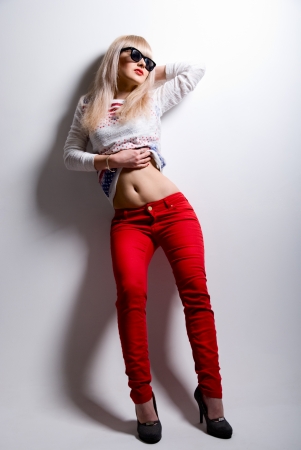 Portrait of a young beautiful blonde in sunglasses. The girl in full growth bares bellyの写真素材