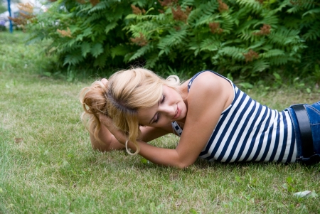 Pensive woman lying on grass. The girl in a striped T-shirtの写真素材
