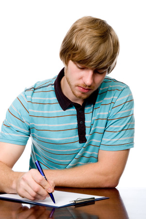 Serious young man sitting at a desk. isolated on white backgroundの写真素材