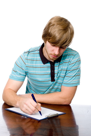 Serious young man sitting at a desk with a pen in hand. isolated on white backgroundの写真素材