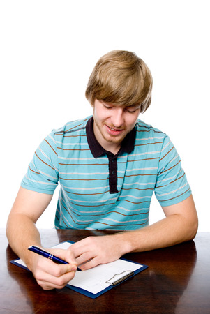 Cheerful young man sitting at a desk with a pen in hand. isolated on white backgroundの写真素材