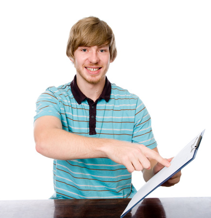 Happy young man points a finger at a blank sheet of sitting at the table. Isolated on white backgroundの写真素材