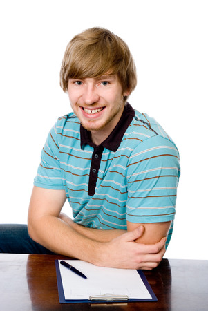Portrait of a cheerful young man sitting behind a desk. isolated on white backgroundの写真素材