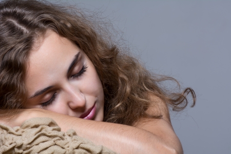 Portrait of a girl with her eyes closed. Isolated on gray backgroundの写真素材