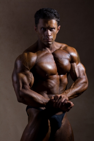 Young sports guy with a naked torso against a dark background.の写真素材