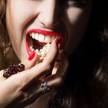 Close-up of young beautiful girl with her ââmouth open and popcorn. Beautiful healthy white teeth. The square frame formatの写真素材