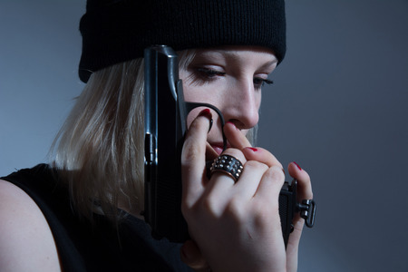Young girl in a dark cap with a gun in his hand.の写真素材