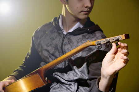 Young man sitting guitar tuning.の写真素材