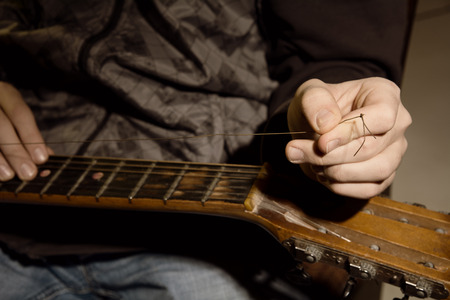Close-up of a man with a guitar string is torn.の写真素材