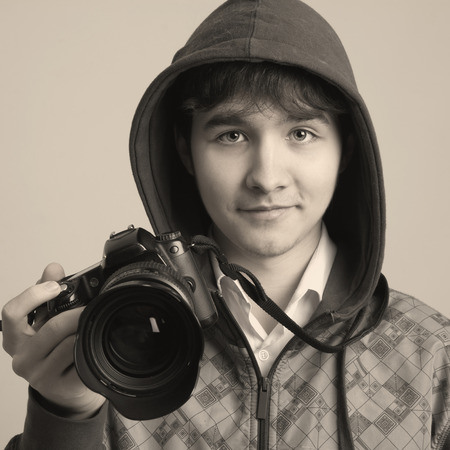 Portrait of a young photographer with a professional camera. Isolated on a light の写真素材