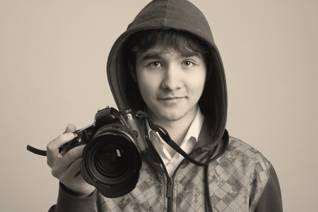 Portrait of cheerful young photographer with a professional camera. Isolated on a light の写真素材