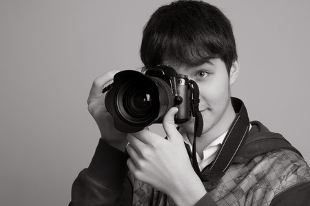 Portrait of cheerful young photographer with a professional camera. Isolated on a light backgroundの写真素材
