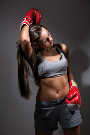 Young beautiful tired woman during fitness and boxing, a dark backgroundの写真素材