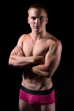Portrait of a young muscular guy on dark backgroundの写真素材