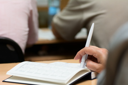 Close-up of a female hand with a pen. Hand on diary during business meetingsの写真素材