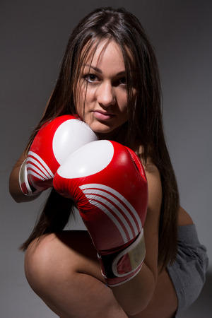 Girl with boxing gloves, dark hair. On a dark background.の写真素材