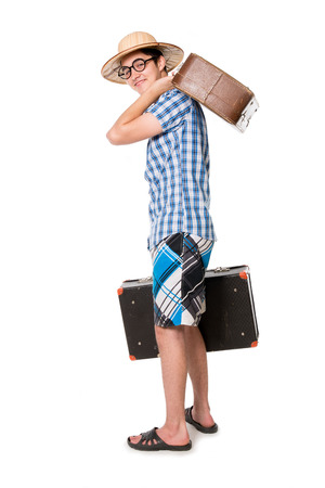 A young, attractive gay guy with glasses and two suitcases ready to travel. The stereotype of a foolish novice traveler. Portrait of a traveler in a full-length isolated on white backgroundの写真素材