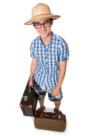 A young, attractive gay guy with glasses and two suitcases ready to travel. The stereotype of a foolish novice traveler. Portrait of a traveler in a full-length isolated on white backgroundの写真素材