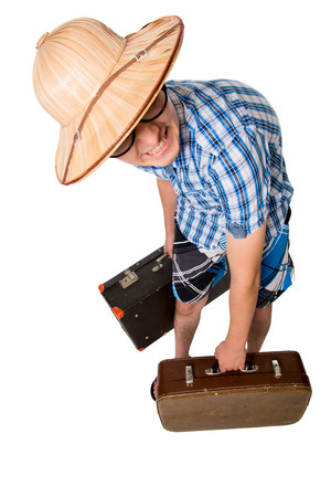 A young attractive man with glasses and two suitcases ready to travel. The stereotype of a foolish novice traveler. Portrait of a traveler in a full-length isolated on white backgroundの写真素材