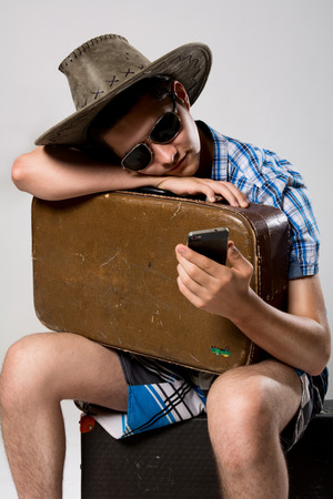 Man with a suitcase is waiting phone call. A young man wearing a hat and sunglassesの写真素材