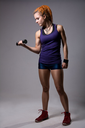 A young girl with dreadlocks training with dumbbells. Athlete fitness full-lengthの写真素材