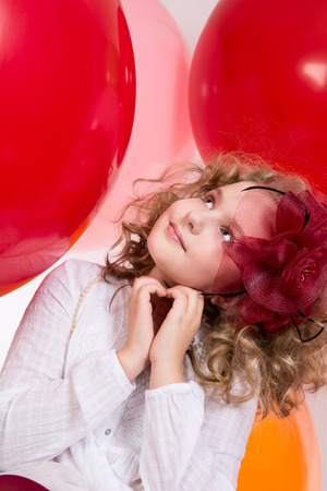 Surprised girl in red hat looking up against the big balloonsの写真素材