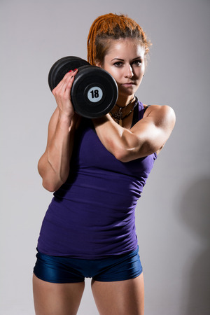 Girl with heavy dumbbell in studio. The concept of power, sport, health. Hand holding a dumbbell.の写真素材