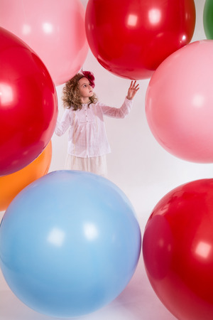 Beautiful girl in a white blouse is considering large balloons. Holiday schoolgirlの写真素材