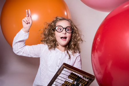 Girl schoolgirl with a surprised look with wooden abacus. Clever girl on a rubber ball
