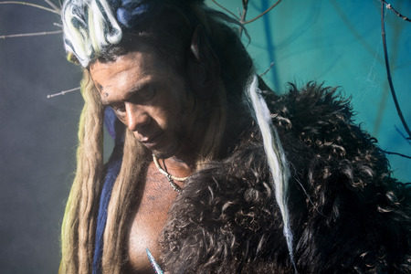 Portrait of pensive man werewolf with a skin on the shoulder and with dreadlocksの写真素材