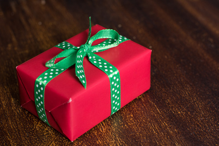Red gift box lies on a wooden background.の写真素材